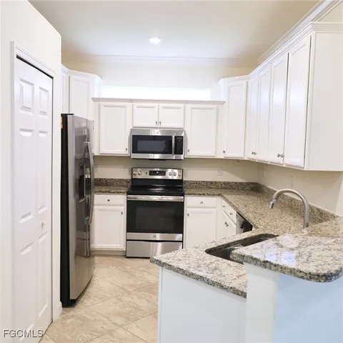 a kitchen with granite countertop a sink stove and refrigerator