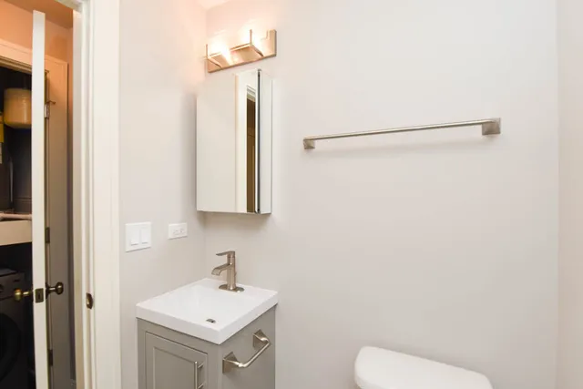 a bathroom with a sink vanity mirror and toilet