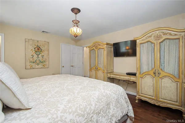 a bedroom with a bed dresser and painting on the wall