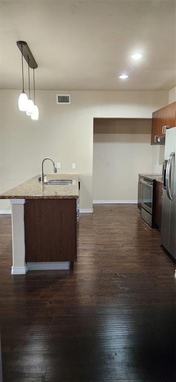 1100 West Trinity Mills Road, Unit 3003 Carrollton, TX 75006 - Photo 15 of 26 a kitchen with kitchen island stainless steel appliances a sink stove and wooden floor
