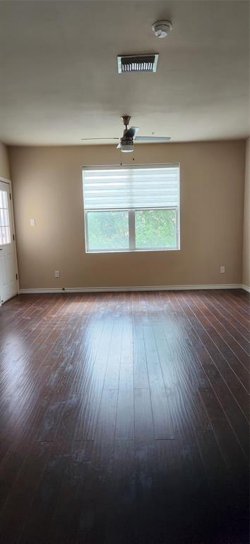 1100 West Trinity Mills Road, Unit 3003 Carrollton, TX 75006 - Photo 16 of 26 an empty room with wooden floor chandelier fan and windows
