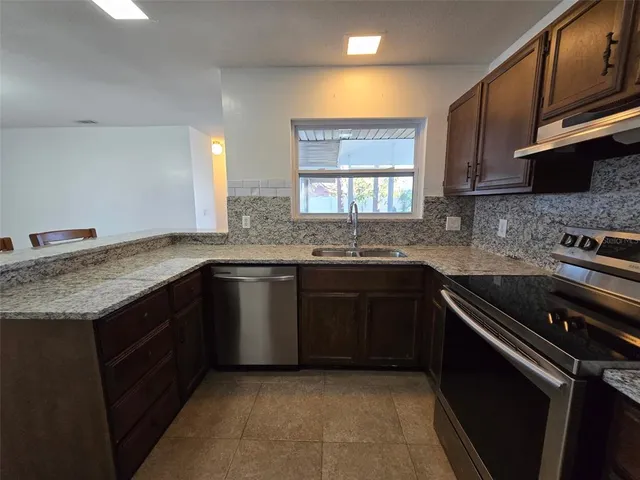 a kitchen with granite countertop a sink stove and cabinets