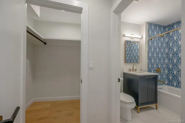 a bathroom with a granite countertop bathtub shower sink vanity and toilet