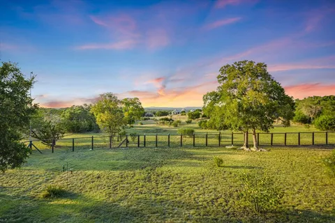 a view of a house next to a big yard and large trees