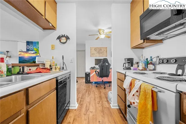 a kitchen with stainless steel appliances granite countertop a sink dishwasher stove refrigerator and couches with wooden floor