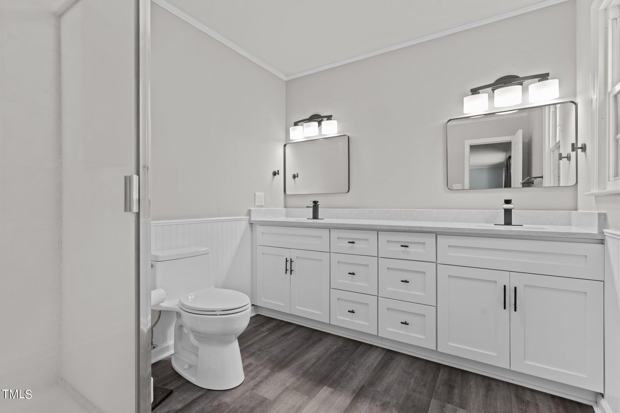 1224 Hedrick Drive Henderson, NC 27537 - Photo 20 of 32 a bathroom with double vanity sink a toilet and a mirror
