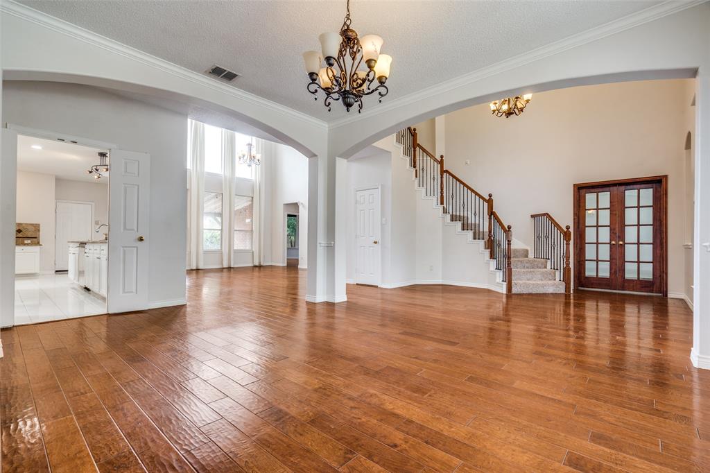 3421 Neiman Road Plano, TX 75025 - Photo 5 of 40 Unfurnished living room featuring a chandelier, arched walkways, light wood-type flooring, stairway, and crown molding
