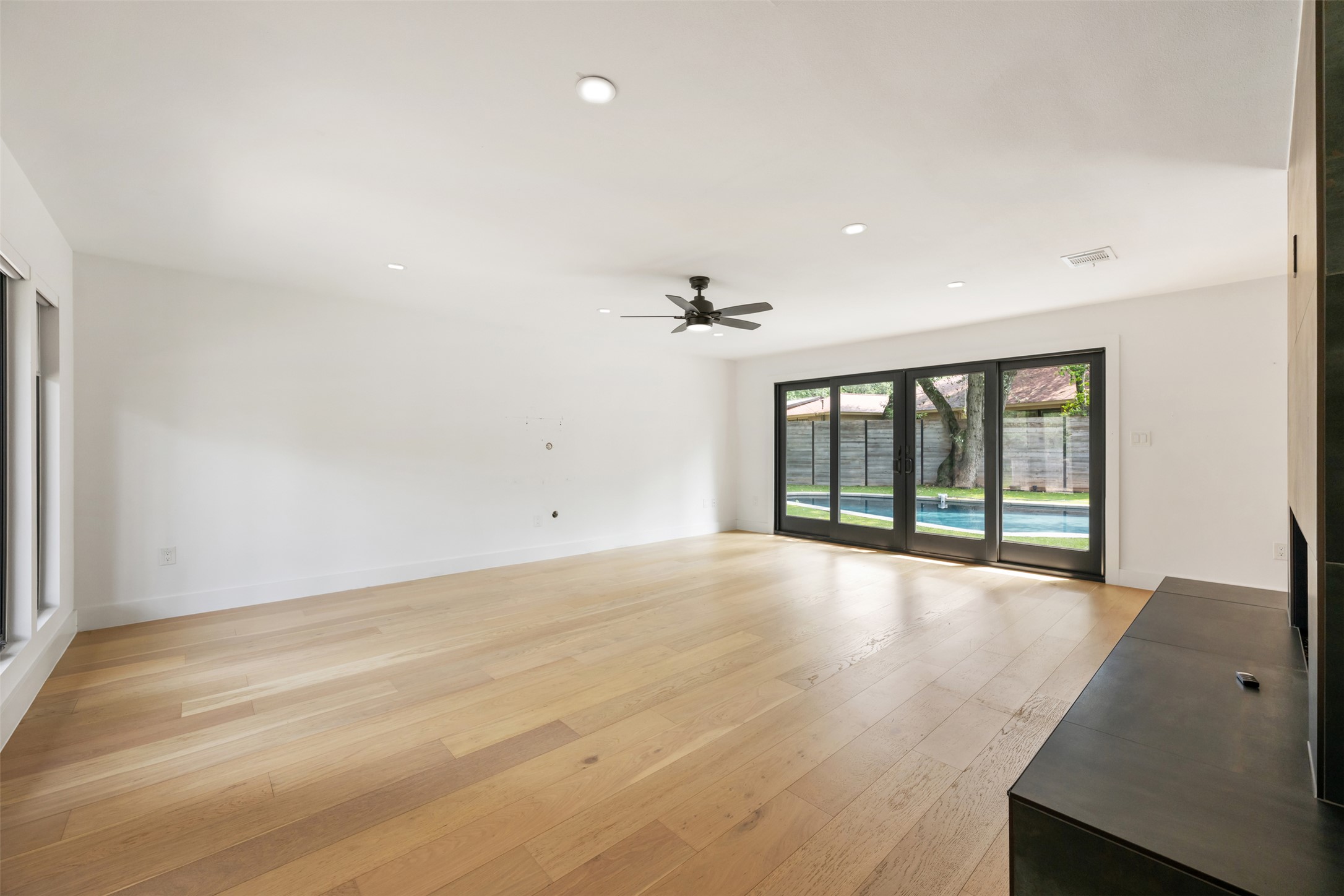 8900 Point W Drive Austin, TX 78759 - Photo 10 of 40 Blonde wood flooring and recessed lighting illuminate this spacious living area with sliding glass doors leading to a private pool.