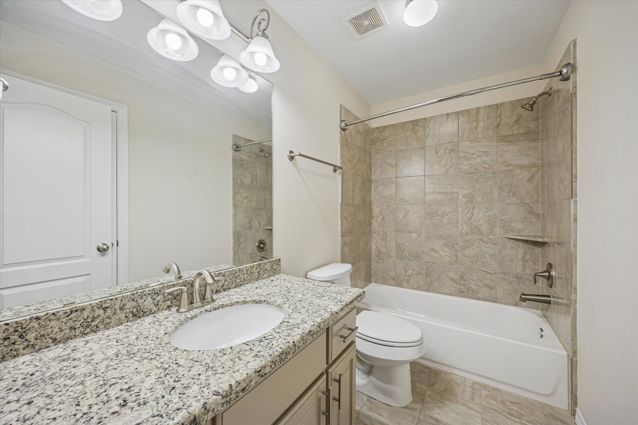1113 Peden Street, Unit B Houston, TX 77006 - Photo 17 of 19 a bathroom with a granite countertop sink a toilet a mirror a bathtub and shower