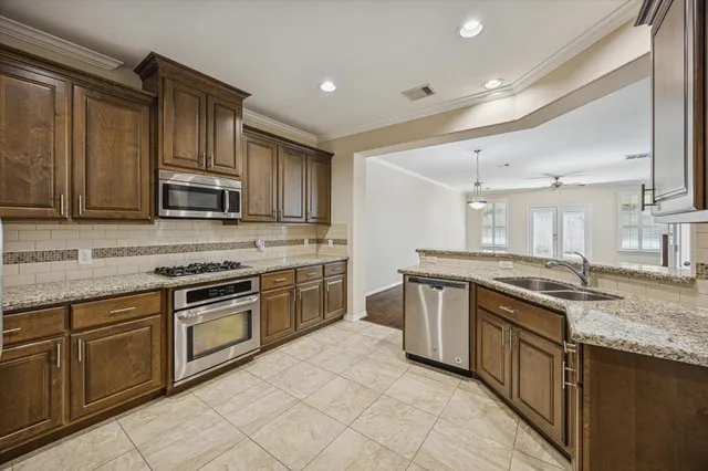 a kitchen with stainless steel appliances granite countertop a stove top oven sink and cabinets