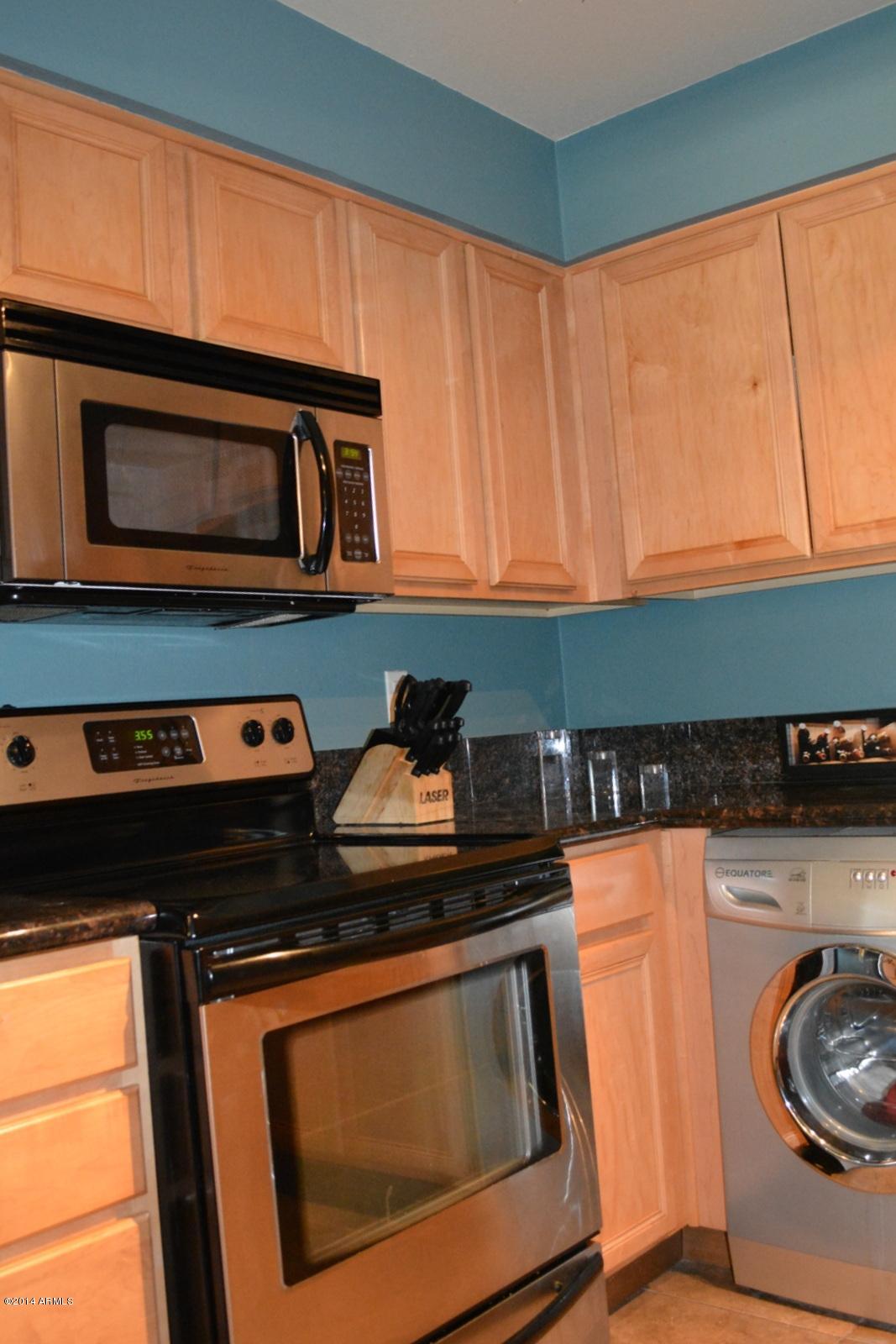 5401 East Thomas Road, Unit 1032 Phoenix, AZ 85018 - Photo 13 of 34 a kitchen with granite countertop a stove top oven cabinetry a sink and a microwave