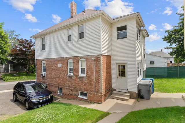 a front view of a house with a garden and chairs