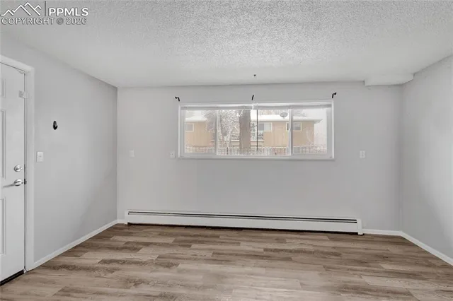 a view of an empty room with wooden floor and a window