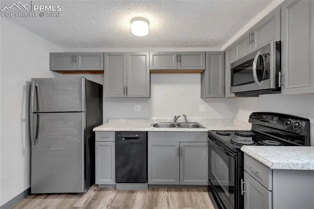 a kitchen with stainless steel appliances granite countertop a refrigerator stove a sink and dishwasher with wooden floor