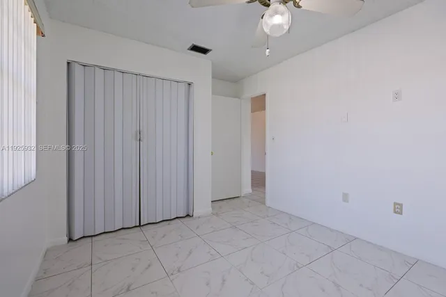 a view of an empty room with a chandelier fan
