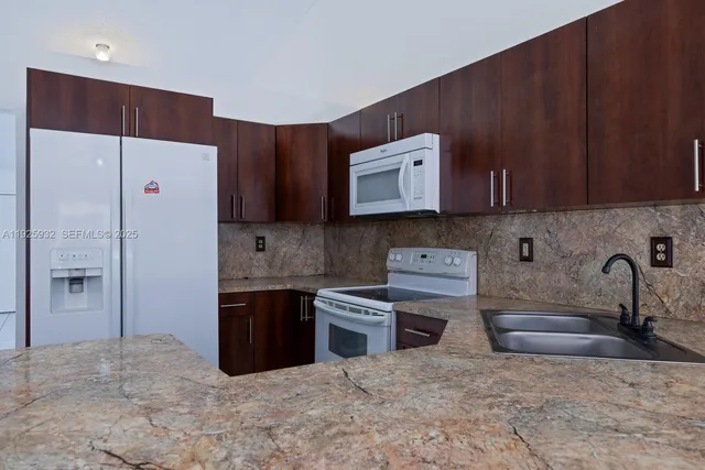 a kitchen with stainless steel appliances granite countertop a refrigerator and a stove top oven