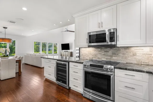 a kitchen with stainless steel appliances granite countertop wooden cabinets a sink a stove a refrigerator and island