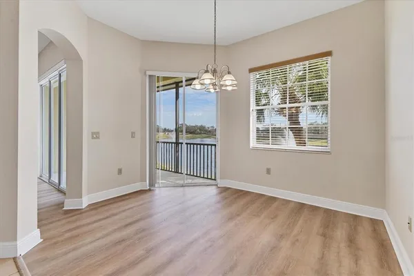 an empty room with wooden floor a ceiling fan and windows