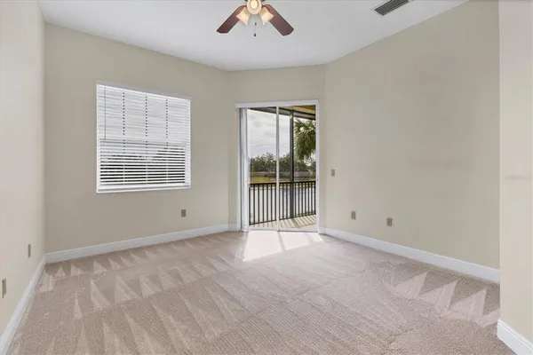 an empty room with chandelier fan and windows