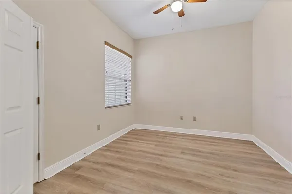 an empty room with a ceiling fan and wooden floor