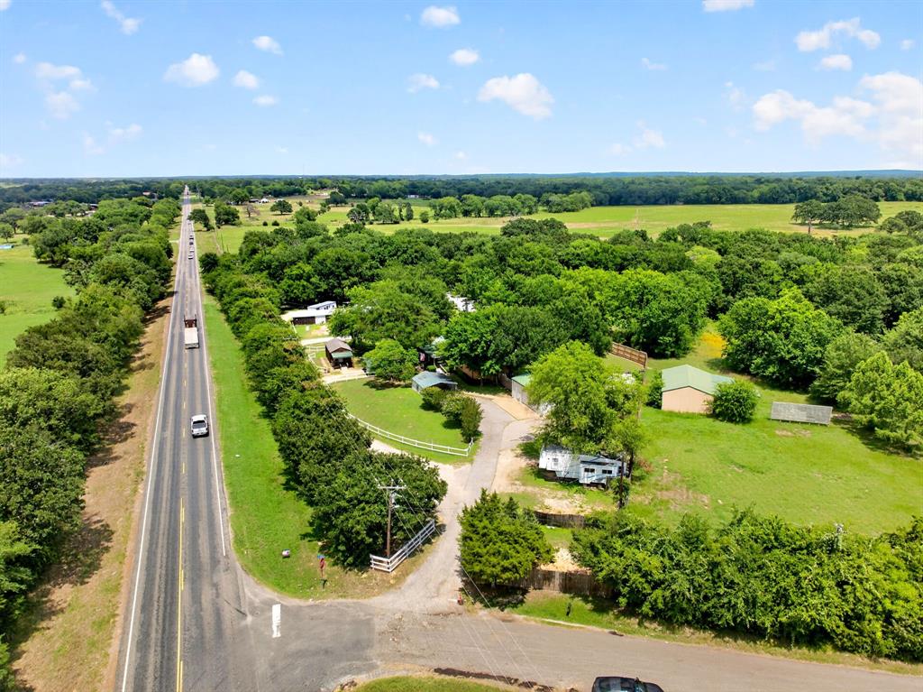 111 County Road 2806 Mabank, TX 75147 - Photo 3 of 34 Expansive property featuring a paved road frontage, established tree line, multiple structures, open green spaces, and a gravel drive