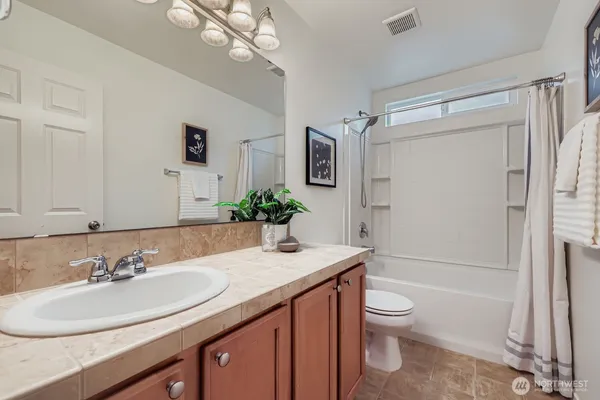 a bathroom with a granite countertop sink toilet a mirror a vanity and shower