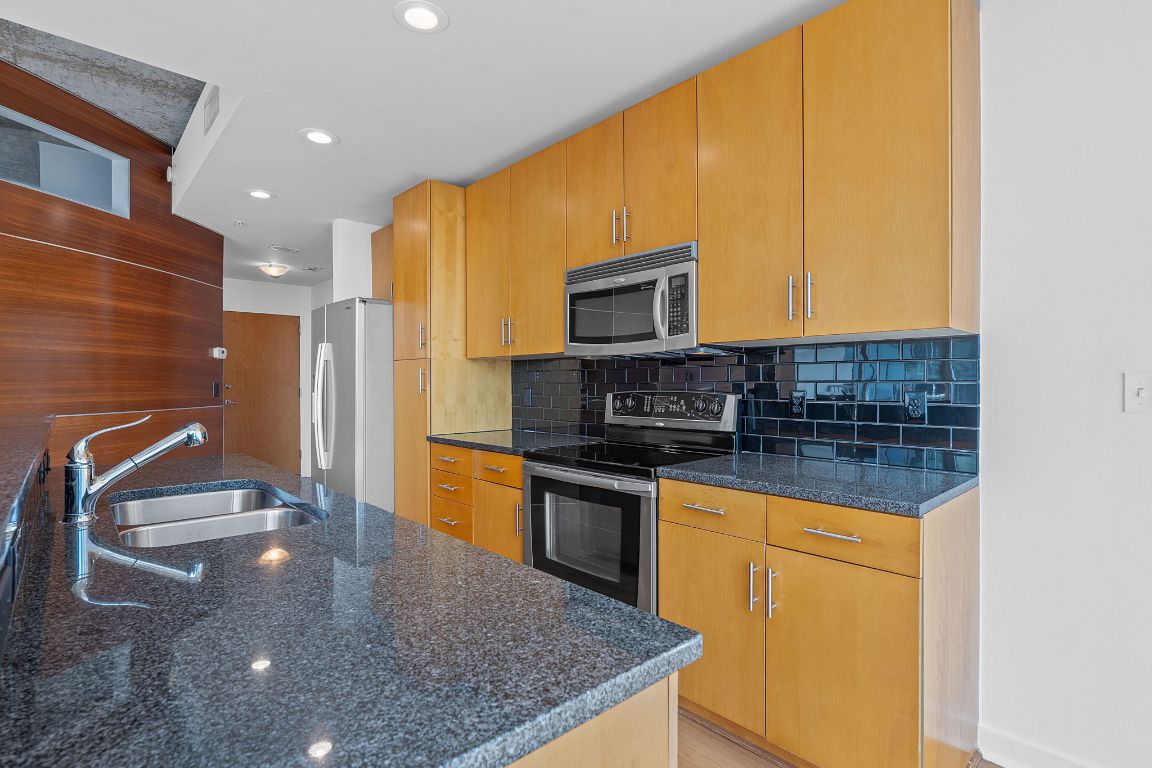 360 Nueces Street, Unit 2401 Austin, TX 78701 - Photo 11 of 40 a kitchen with stainless steel appliances granite countertop a sink a stove and a microwave