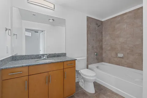 a bathroom with a granite countertop bathtub shower sink mirror and toilet