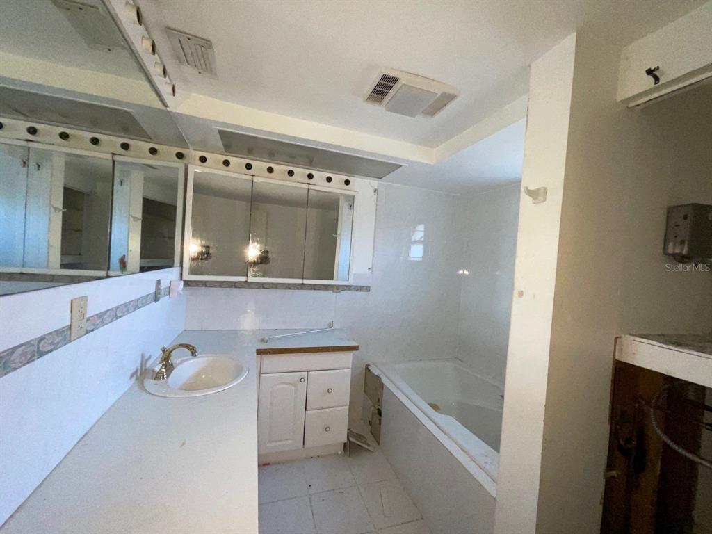 15839 Hicks Road Hudson, FL 34667 - Photo 10 of 16 a bathroom with a tub a sink and mirror