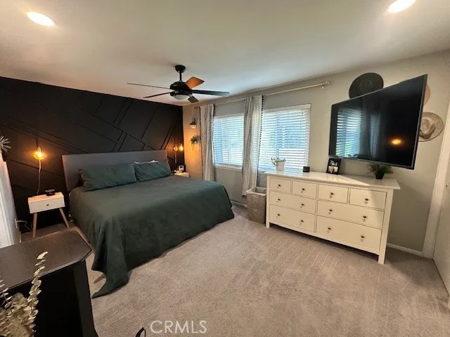 a bedroom with a bed a mirror on dresser and a flat screen tv