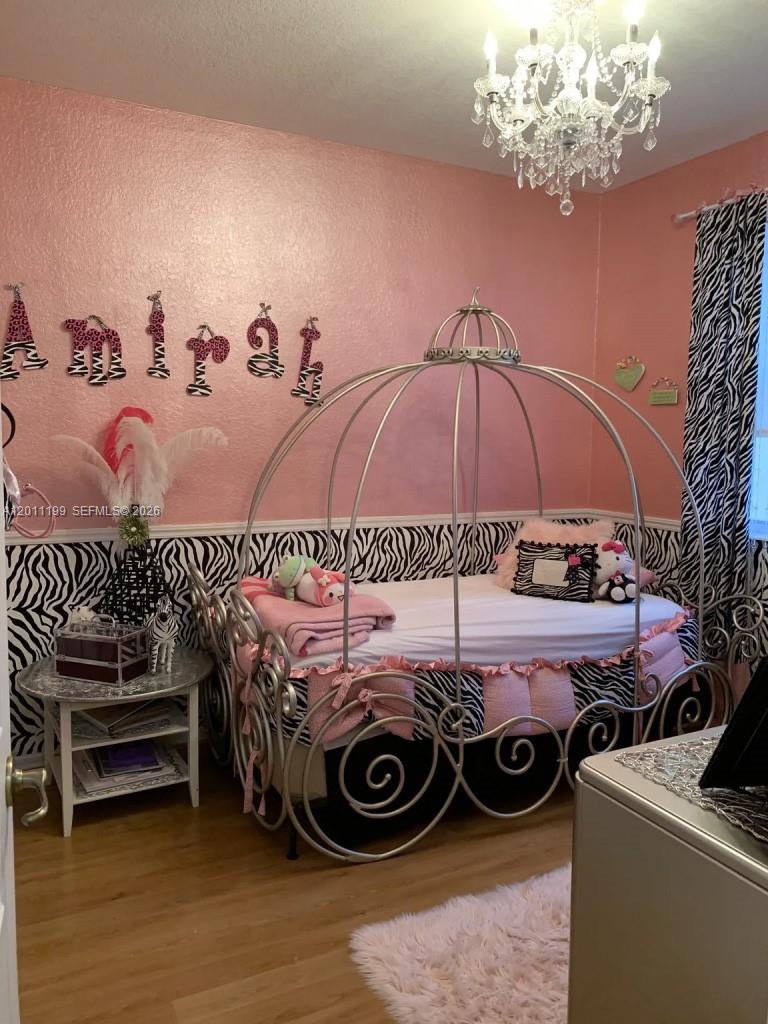 12450 Southwest 125th Terrace, Unit 12450 Miami, FL 33186 - Photo 3 of 23 a bedroom with a bed and a chandelier