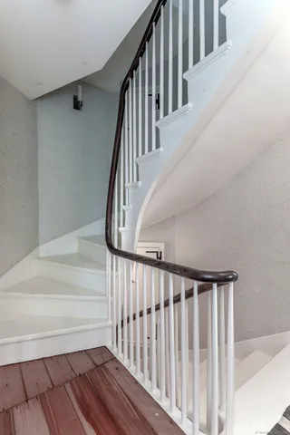 a view of staircase with wooden floor and white walls
