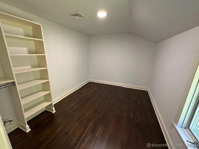 a view of an empty room with wooden floor and stairs