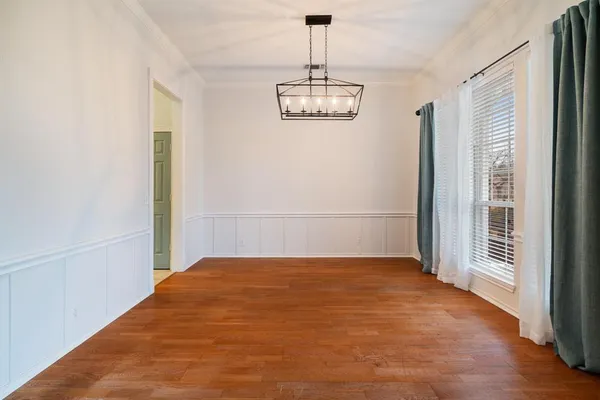 a view of a room with wooden floor chandelier and windows