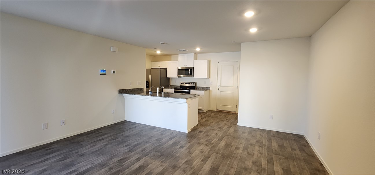 9127 Rory Storm Street Las Vegas, NV 89113 - Photo 3 of 27 Granite countertops and wood-look flooring enhance the open concept kitchen and living area.