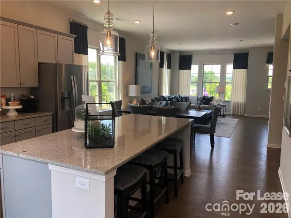 a kitchen with stainless steel appliances granite countertop a stove a refrigerator a sink a dining table and chairs