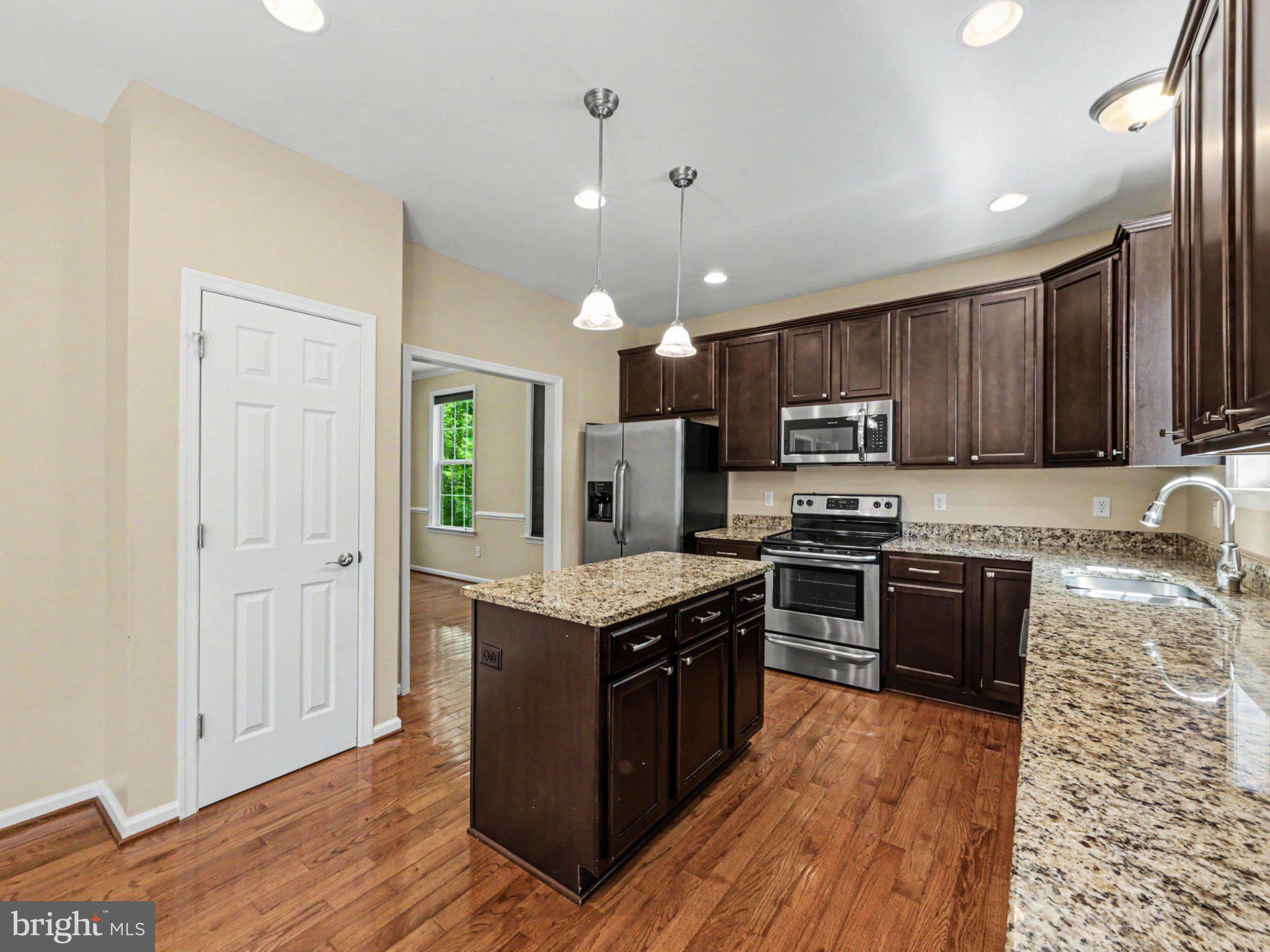 9811 Catharpin Road Spotsylvania, VA 22551 - Photo 10 of 30 a kitchen with granite countertop wooden floors and stainless steel appliances