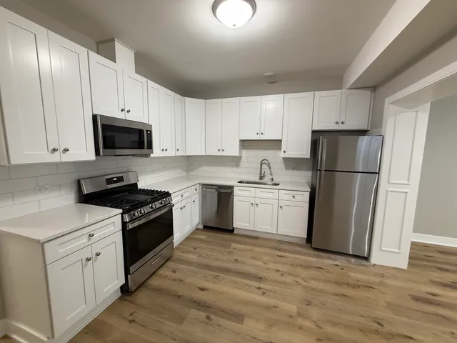 a kitchen with a refrigerator stove and white cabinets