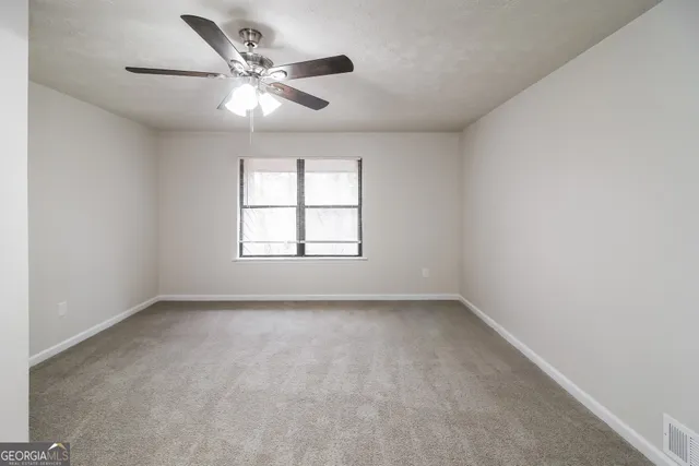 an empty room with windows and ceiling fan
