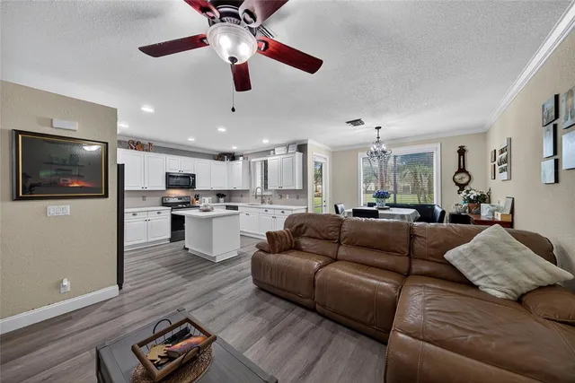 a living room with couches and kitchen view with wooden floor