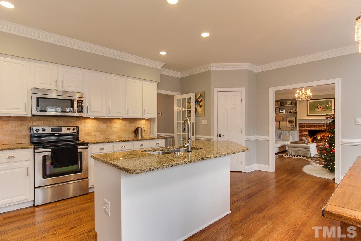 7904 Ogden Court Raleigh, NC 27613 - Photo 11 of 25 a kitchen with stainless steel appliances granite countertop a stove top oven a sink dishwasher a refrigerator and white cabinets with wooden floor