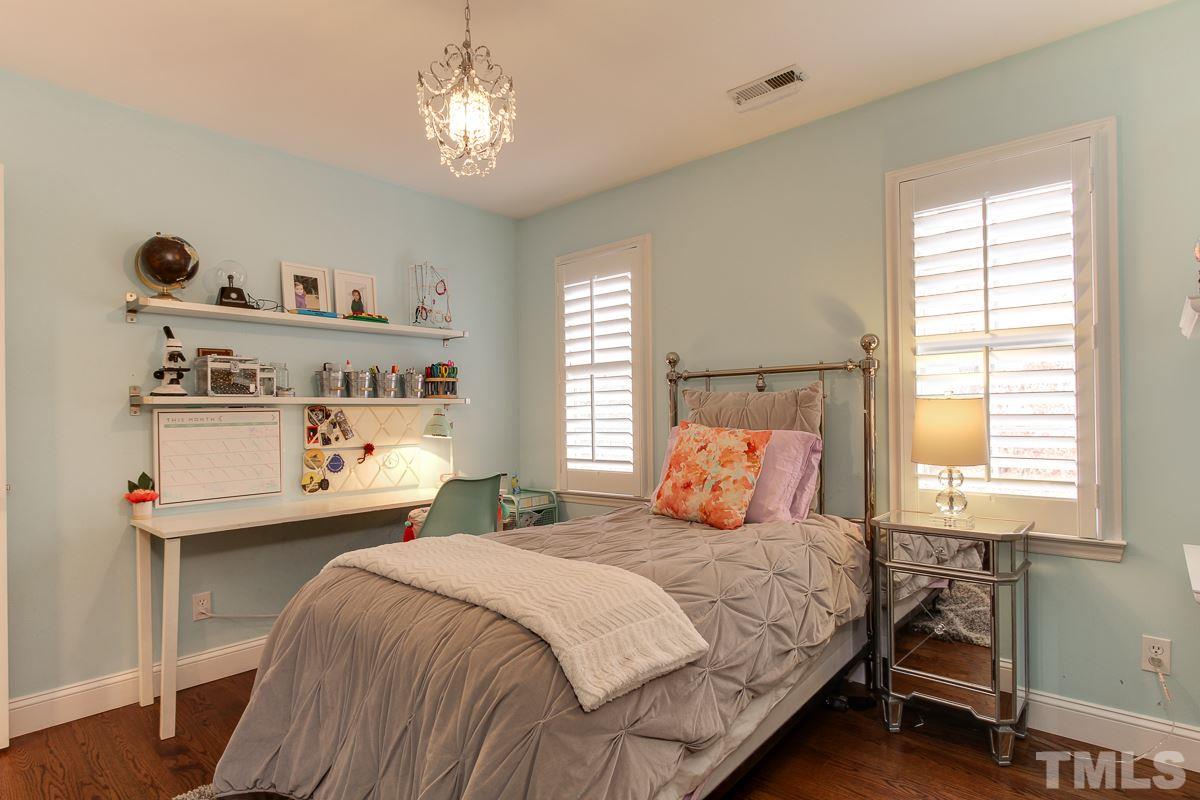 7904 Ogden Court Raleigh, NC 27613 - Photo 19 of 25 a bedroom with a bed and a chandelier