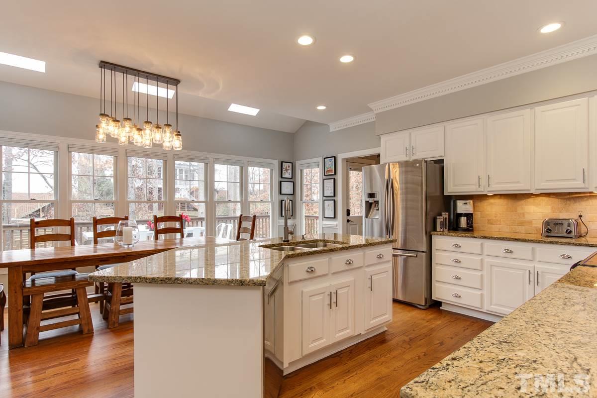 7904 Ogden Court Raleigh, NC 27613 - Photo 9 of 25 a large white kitchen with granite countertop a stove a sink a refrigerator and white cabinets with wooden floor