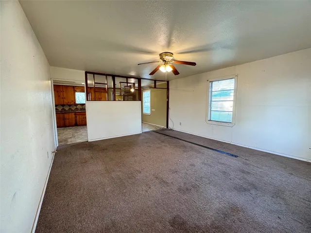 en empty room with windows and ceiling fan