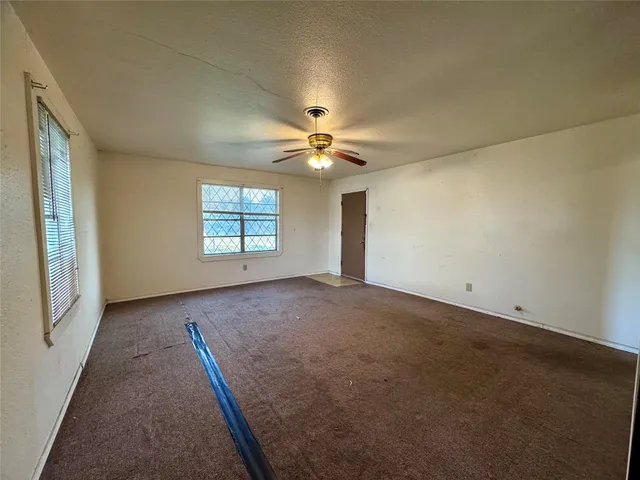 an empty room with windows and ceiling fan
