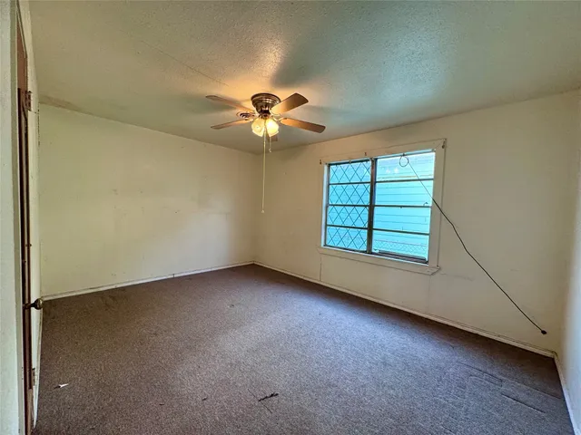 an empty room with windows and chandelier fan