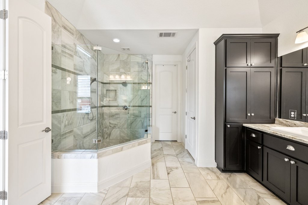 5812 Davenport Divide Road Austin, TX 78738 - Photo 25 of 40 From this angle, you can see the scale — separate vanities, tall storage cabinetry, and a deep soaking tub tucked into its own corner. It’s spacious, polished, and thoughtfully laid out.
