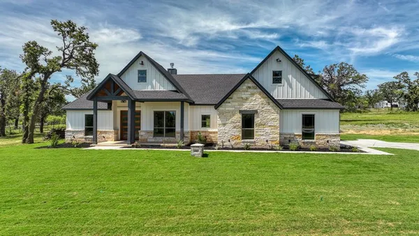 a front view of a house with a garden and trees