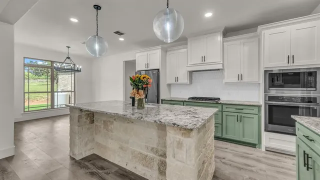 a kitchen with stainless steel appliances granite countertop a sink a stove a refrigerator and island with wooden floor