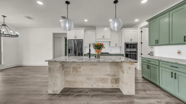 a large kitchen with granite countertop a stove a sink and a refrigerator